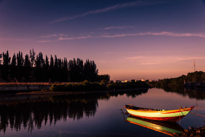 Boat moored with reflection in lake against purple sky