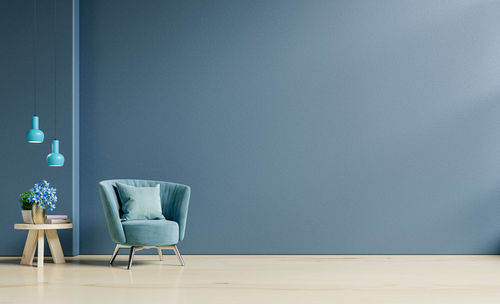 Living room interior mockup in warm tones with armchair on empty dark blue wall background.