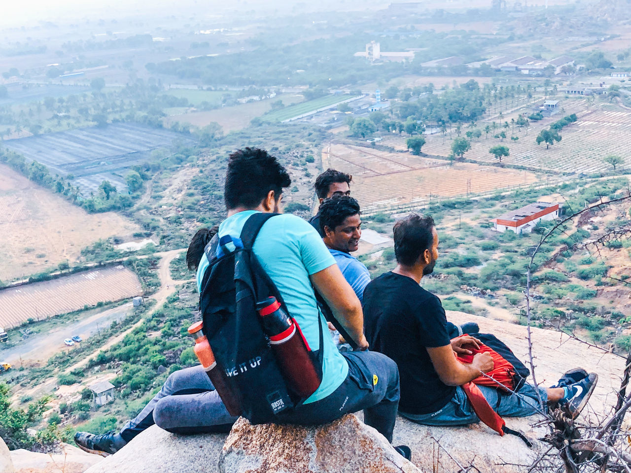 PEOPLE SITTING ON MOUNTAIN LOOKING AT MOUNTAINS