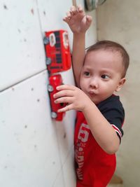 Portrait of cute boy looking away against wall