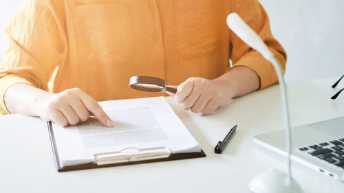 Midsection of woman reading book on table