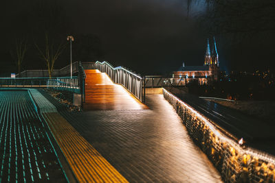 View of illuminated footbridge in city at night