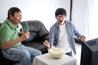 Family with food and drink watching sports on tv at home