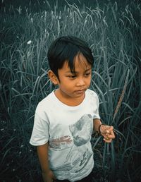 Boy looking away while sitting on land