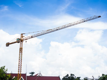 Low angle view of crane at construction site against sky