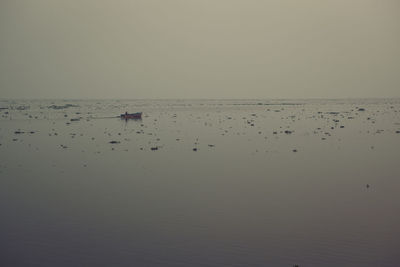 Mid distance view of boat sailing on sea against sky during foggy weather