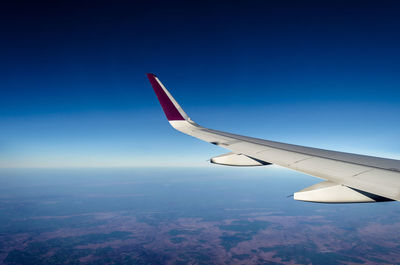 Aerial view of airplane wing against blue sky