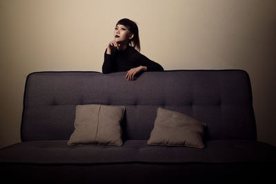 Young woman sitting on sofa at home