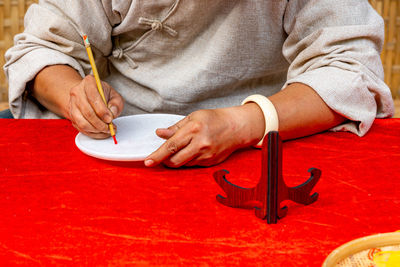 Midsection of man holding red chili peppers on table