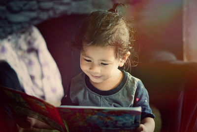 Cute girl looking away while using mobile phone at home