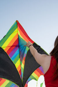 Midsection of woman holding umbrella against clear sky