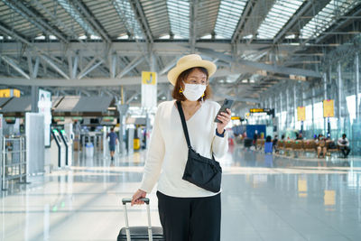 Woman holding camera while standing at airport