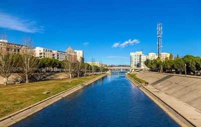River by buildings against blue sky