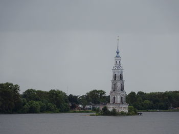 Tower amidst trees and building against sky