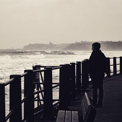 Rear view of man looking at sea against sky