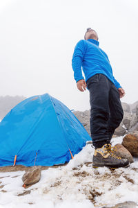 Rear view of man sitting on rock against clear sky