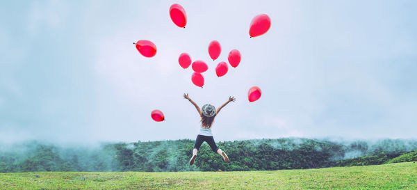 Low angle view of woman with balloons against sky