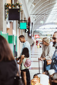 Man with family buying tickets from automated machine at train station