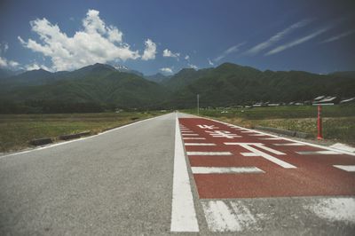 Road sign by street against mountains