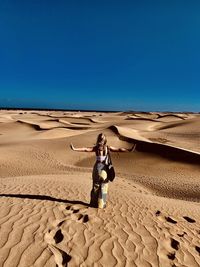Woman standing on desert against clear sky
