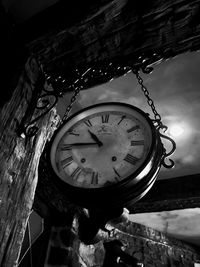Low angle view of clock hanging on wood