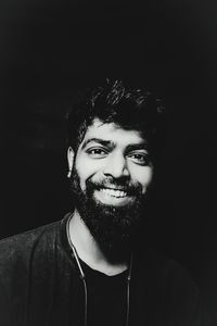 Portrait of smiling young man against black background