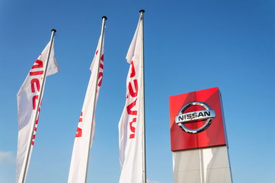 Low angle view of flags against clear blue sky