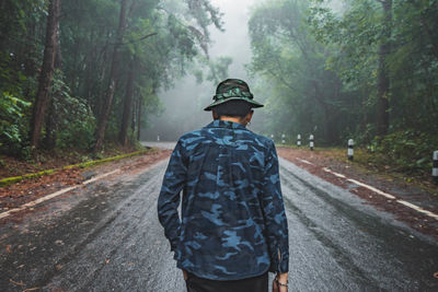 Rear view of man walking on road in forest