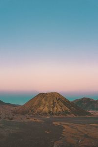 Scenic view of arid landscape against clear sky during sunset