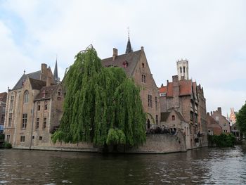 Buildings by river against sky