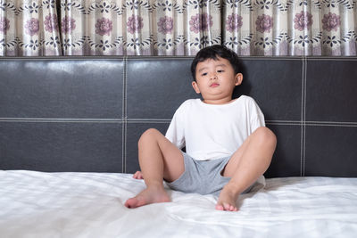Portrait of cute girl sitting on bed at home