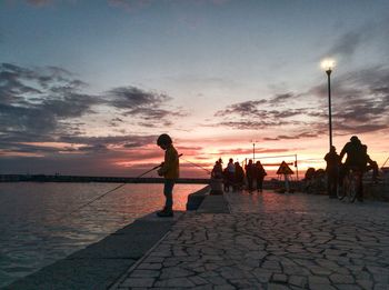 Silhouette people on beach against sky during sunset