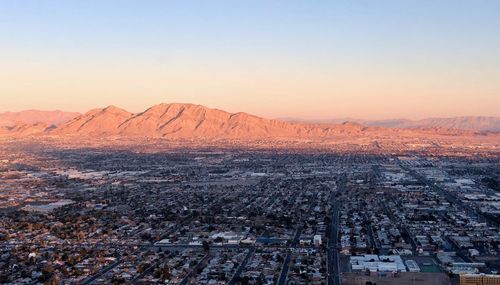 Aerial view of city by mountain against clear sky