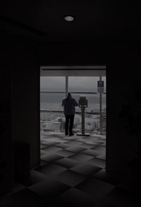 Rear view of man looking through window