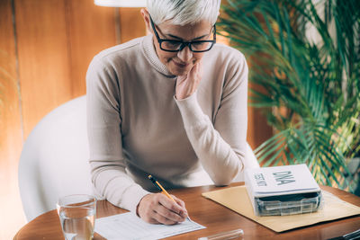 Midsection of woman holding paper while sitting on table