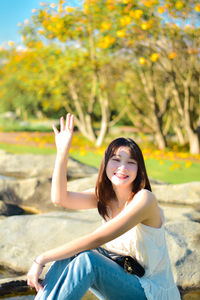 Portrait of young woman sitting on retaining wall