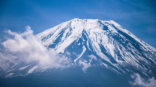 Scenic view of snowcapped mountains against blue sky