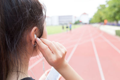 Close-up of athlete listening to music on headphones at running track