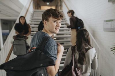 Portrait of smiling male student with friends at university