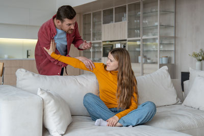 Young woman using phone while sitting on bed at home