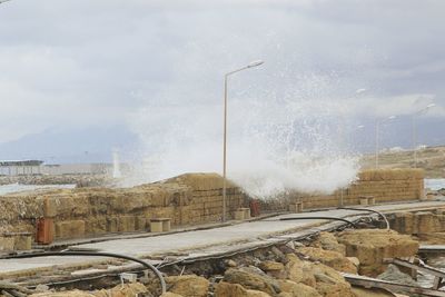 Sea waves splashing on rocks against sky