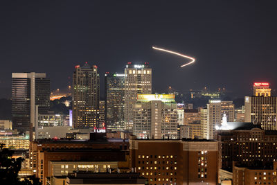 Illuminated buildings in city against sky at night