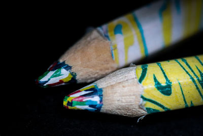 Close-up of multi colored pencils on table against black background