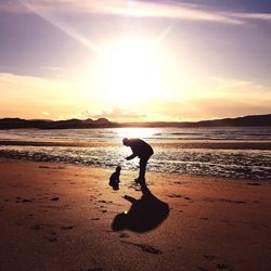 Silhouette person on beach against sky during sunset