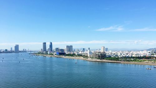 City at waterfront against blue sky