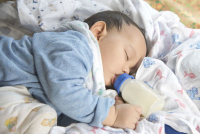 Cute baby drinking milk while sleeping on bed