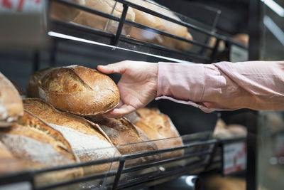 Close-up of man picking bread in bakery section of supermarket