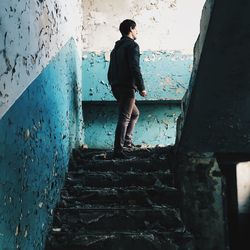 Low angle view of man walking on staircase at abandoned building