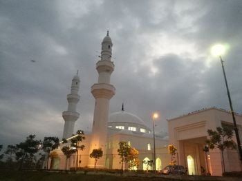 Low angle view of illuminated building against cloudy sky