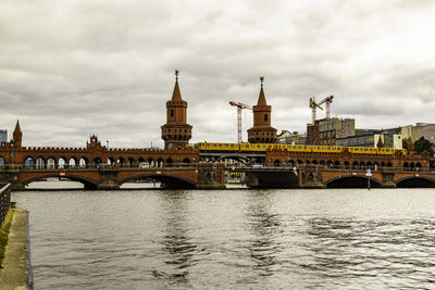 Arch bridge over river against cloudy sky